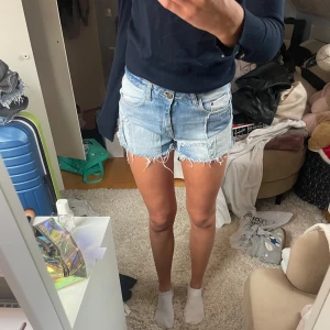 Jeansshorts med fransar - Snygga ljusblå jeansshorts med fransiga kanter och klassisk femficksdesign. Perfekta för sommardagar och avslappnade stunder. De har en bekväm passform och är ett måste i garderoben för en cool och avslappnad stil.