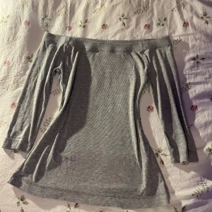 Grå offshoulder topp från Gina Tricot - Säljer en stilren grå offshoulder topp från Gina Tricot. Toppen är ribbad och har trekvartsärmar, perfekt för en avslappnad look. Passar bra till jeans eller kjol för en trendig outfit.