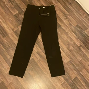 Svarta byxor med dragkedja - Snygga svarta byxor med dragkedja framtill. Perfekta för en stilren look. Storlek 34. Kostym byxor.