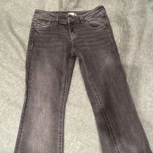 Grå jeans från Gina Tricot - Snygga grå jeans från Gina Tricot med broderade detaljer på bakfickorna. De har en klassisk femficksdesign och en knappgylf. Perfekta för en avslappnad stil.