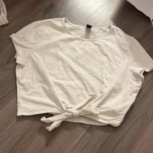 Vit kortärmad topp med knyt från shein  - Säljer en vit kortärmad topp med knyt framtill. Perfekt för en avslappnad stil. Toppen har en rund halsringning och är gjord i ett mjukt material.