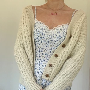 Beige stickad kofta från Brandy Melville - Mysig beige stickad kofta från Brandy Melville med kabelstickat mönster och knappar framtill. Perfekt för lager-på-lager och ger en avslappnad look. :) 