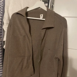 Beige cardigan med dragkedja - Snygg beige cardigan från Åhlens med dragkedja och två stora fickor framtill. Den endast använd en gång. Den är väldigt skön i materialet och kan användas till att klä upp och ner en outfit, perfekt! Jag säljer denna eftersom att jag köpte den men aldrig fick använding då jag har antal liknande💕 Köp gärna och tveka inte att stälka frågor!