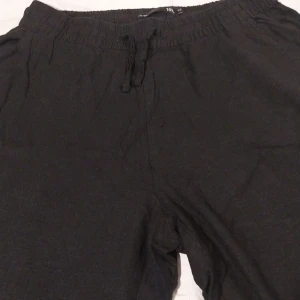 Svarta linnebyxor från 157 - Säljer ett par svarta linne byxor från 157 i storlek XS. Byxorna har en elastisk midja med snörning för extra komfort. Perfekta för en avslappnad stil.