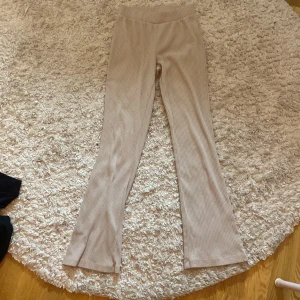 Beige ribbade byxor från Xoo Friends - Säljer ett par snygga beige ribbade byxor från ullared . Byxorna har en tight passform och är perfekta för en stilren look. De är tillverkade i ett mjukt och bekvämt material.