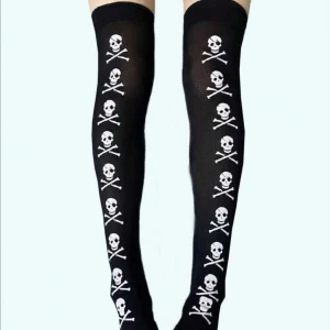 Svarta knästrumpor med dödskallemotiv - Snygga svarta knästrumpor med ett coolt dödskalle- och korslagda benknotor-mönster i vitt längs hela strumpan. Perfekta för att ge din outfit en edgy touch. Tillverkade i ett mjukt och stretchigt material för bästa komfort. ALDRIG ANVÄNDA 