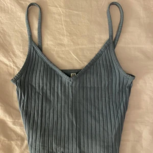 Blå ribbad linnetopp från H&M Divided - Snygg blå ribbad linnetopp från H&M Divided med smala axelband och v-ringning. Passar även de med str XS samt S. Säljer då jag inte använder längre.