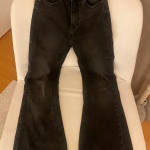 Mörkgrå  jeans från Pull&Bear - Snygga svarta jeans från Pull&Bear i storlek EUR 34. De är långa, högmidjade och bootcut. De är i mycket bra skick, dock har det lite slitage längst ner på båda benen.