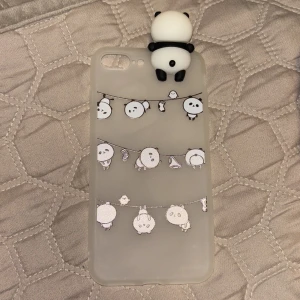 Söt mobilskal med panda-design - Ett gulligt mobilskal med en 3D-panda på toppen och små pandor hängande på linor. Skalet är genomskinligt med en mjuk finish, perfekt för att ge din telefon en lekfull touch. Är i helt nytt skick och aldrig använd, passar iphone 6+, iphone 7+ och iphone 8+