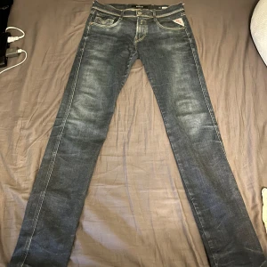 Mörkblå jeans från Replay - Snygga mörkblå jeans från Replay, modell Anbass. De har en klassisk femficksdesign med knappgylf och kontrastsömmar. Perfekta för en stilren look. Waist 30 längd 32, mycket bra skick 
