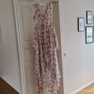 Blommig långklänning från Y.A.S - Säljer en vacker blommig långklänning från Y.A.S. Klänningen har volanger och en omlott-design med en romantisk känsla. Perfekt för sommarens festligheter.