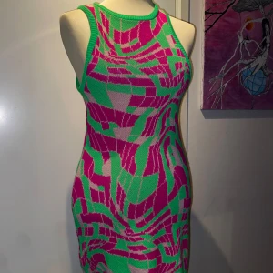 Färgglad stickad klänning - Snygg och färgglad stickad klänning med ett unikt mönster i rosa och grönt. Klänningen är ärmlös och har en tight passform som framhäver kroppens figur. Är varm och mysig, väldigt mjuk! :) 