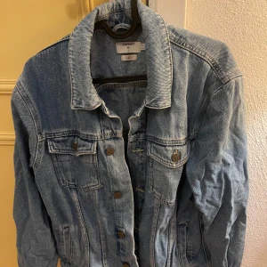 Blå jeansjacka från Topman stl S - Snygg blå jeansjacka från Topman med klassisk design. Jackan har knappar framtill och två bröstfickor med knappstängning. Perfekt för en avslappnad stil.