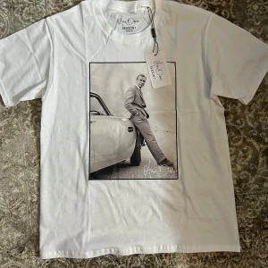 Vit t-shirt med tryck från Ame Doree - Snygg vit t-shirt från Ame Doree med ett stilrent svartvitt tryck av en man vid en bil. Perfekt för en casual look. T-shirten gjord i mjukt material och är i storlek S . Helt ny T-shirt som är aldrig använd . Nypris ligger på 500kr