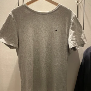Grå t-shirt från Morris - Snygg grå t-shirt från Morris med en liten broderad detalj på bröstet. Fint skick men lite uttöjd runt kragen.