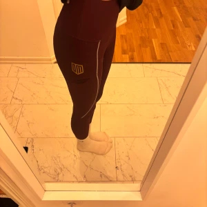Vinröda ridbyxor från maya delorez - Snygga vinröda leggings med hög midja och maya delorez logan i guld på benen. Perfekta för ridning eller bara att vara i stallet. De har en tight passform och är gjorda i ett stretchigt material för bästa komfort. De är halvskodda men vädligt sköna! Gripet är inte alls slitet. Orginal pris 799