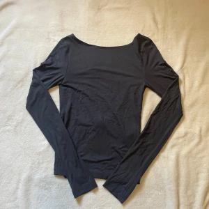 Svart långärmad backless topp från Gina Tricot - Snygg svart långärmad topp från Gina Tricot med en djup öppen rygg. Perfekt för en stilren look. Tillverkad i ett mjukt och bekvämt material.