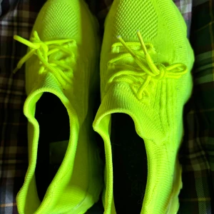 Neongula sneakers - Snygga neongula sneakers med stickad ovandel och robust sula. Perfekta för att sticka ut i mängden med sin lysande färg och bekväma passform.
