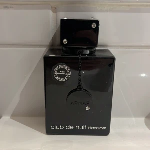 Club de Nuit Intense Man Eau de Toilette - Säljer en elegant och maskulin parfym, Club de Nuit Intense Man från Armaf. Flaskan är svart med en stilren design och en liten kedja som detalj. Parfymen är en Eau de Toilette och kommer i en 105 ml flaska. Perfekt för den som söker en intensiv och långvarig doft. Knappt använd och är ungefär 90% full