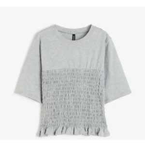 Grå topp med smockdetaljer - Snygg grå topp med smockdetaljer och volangkant. Grå med trekvartsärm.