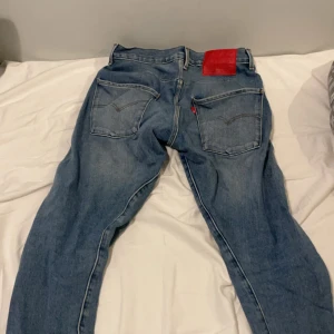 Blå jeansbyxor - Säljer ett par blå levi’s jeans med fem fickor och knappgylf. De har en normal passform och är perfekta för en avslappnad stil. Passar till det mesta i garderoben.