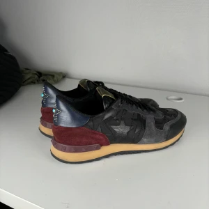 Svarta sneakers från Valentino - Snygga svarta sneakers från Valentino med detaljer i rött och blått. Storleken är 43 och priset ligger på 2499 skick 9 endast dustbag ingår