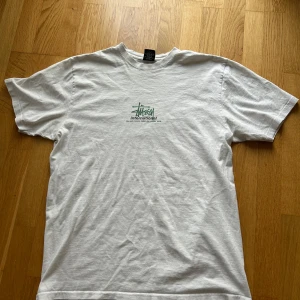 Vit Stüssy T-Shirt - Säljer en vit T-shirt från Stüssy som jag inte använder längre. Har inte använts mycket och är i väldigt fint skick, utan defekter/fläckar. Inköpt från shelta.
