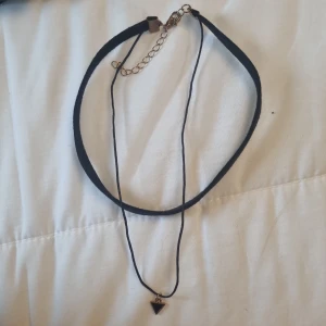 Svart chokerhalsband med triangulärt hänge - Snyggt svart chokerhalsband med ett litet triangulärt hänge i guld och svart. Perfekt för att ge en stilren touch till din outfit. Justerbar kedja för bästa passform. Kontakta vid mått, frågor, intresse eller liknande. ❤️