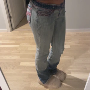 Ljusblå jeans med broderade detaljer - Snygga ljusblå jeans med unika broderade detaljer i rosa på fickorna. De har en klassisk femficksdesign och en bekväm passform. Perfekta för en avslappnad stil.