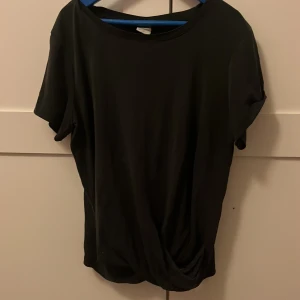 Svart t-shirt från Lindex Kids - Snygg mörkgrå/svart t-shirt från Lindex Kids i storlek 170. Den har en enkel design med korta ärmar och rund halsringning. 