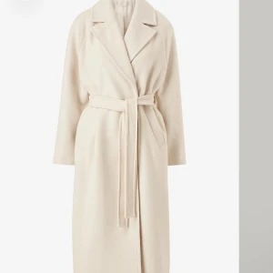 Beige krämvit kappa  - Kappa köpt från Ellos men använd väldigt få gånger. Kappan är i superfint skick och väldigt lång och elegant skriv gärna för fler bilder. Jag bär storlek 36 och har köpt 38 för en liten oversize, modellerna på annonsen hade även storlek 38🤍