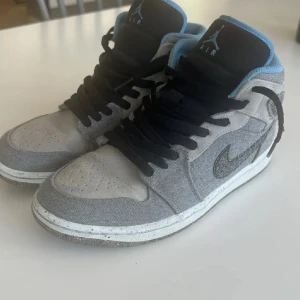 Gråa Nike Air Jordans - Säljer ett par gråa Nike Air Jordans i bra skick. Skorna har en snygg kombination av ljusgrått och mörkgrått tyg med svarta detaljer. De har svarta snören och en vit sula med svarta prickar. Insidan är fodrad med ljusblått tyg för extra komfort. Perfekta för både vardag och träning!