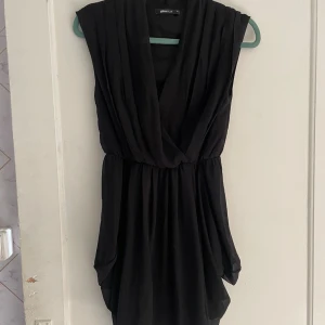 Svart klänning från Gina Tricot - Säljer en snygg svart klänning från Gina Tricot i storlek 34. Klänningen är ärmlös och har en omlott-design framtill som ger en elegant look. Perfekt för fest eller andra speciella tillfällen. Materialet känns mjukt och bekvämt att ha på sig. Köp direkt eller ge prisförslag 💛