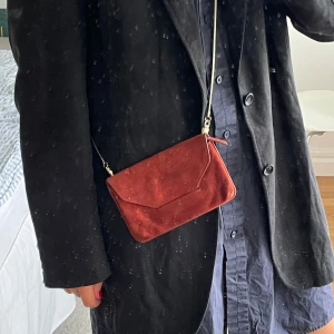 Röd mocka axelväska från Filippa K - Säljer en snygg röd axelväska i mocka från Filippa K i fint skick!