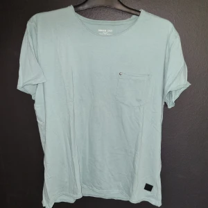 Grön t-shirt från Denim Day - Säljer en grön t-shirt från Denim Day i storlek L. T-shirten har en bröstficka med en liten knappdetalj och är kortärmad. Perfekt för en avslappnad stil!