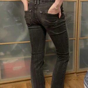 Svarta Lee-jeans lågmidjat - Ett par svarta jeans i riktigt bra skick. Lågmidjade och smått bootcut-aktiga! Midjemått 78 cm Innerbenslängd 76  Kompis står som modell