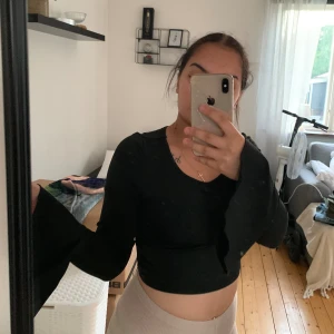 Svart croppad topp med vida ärmar - Säljer en snygg svart croppad topp med vida ärmar. Toppen har en tight passform och är perfekt för fest eller en utekväll. Den är tillverkad i ett mjukt och bekvämt material som känns skönt mot huden. Passar perfekt till både jeans och kjol!