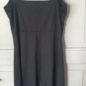 Svart klänning från Soya - Säljer en elegant svart klänning från Soya. Klänningen är i storlek M och har en vacker detalj med svarta pärlor under bysten. Den är ärmlös och har en omlott-design vid bysten. Perfekt för fest eller andra speciella tillfällen. Klänningen är i nyskick och redo att bäras av någon som vill känna sig extra fin!