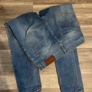 Blå jeans från Tiger of Sweden - Säljer ett par snygga blå jeans från Tiger of Sweden. De är i bra skick och har en klassisk straight fit. Är bra till gricsh, laidback och Stockholmstil.stilnypris 1800 kr säljer för 800kr, kan givetvis ta bättre bilder!