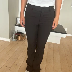 Svarta kostymbyxor - Säljer ett par svarta kostymbyxor i storlek 34.  Byxorna är mid-highwaist och har en bootcut passform.  Materialet känns bekvämt och ser stilrent ut. Min kompis på bilden är 160cm lång men de är lite långa för henne. Köpta för ca 400kr och säljer för 150kr. Köparen står för frakten!!