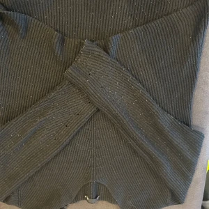 Svart ribbad tröja från ASOS - Säljer en snygg svart ribbad tröja från lager 157. Tröjan har en cool omlott-design framtill som ger den en unik look. Perfekt för höst och vinter, och kan lätt stylas både till vardags och fest. Den är i storlek M och i mycket bra skick. Passa på att fynda denna trendiga tröja!