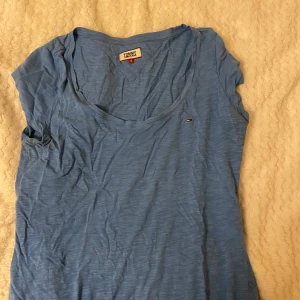 Blå t-shirt från Tommy Jeans - Säljer en snygg blå t-shirt från Tommy Jeans. Den är i storlek S och har en klassisk rund halsringning. Perfekt för vardagsbruk och kan enkelt matchas med jeans eller shorts. T-shirten är i bra skick och har en liten logga på bröstet.