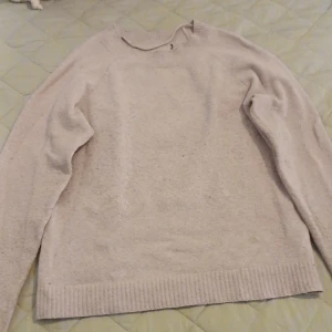  stickad tröja - Säljer en mysig beige stickad tröja med ribbade kanter vid hals, ärmslut och nederkant. Perfekt för kyliga dagar och passar till det mesta i garderoben. Tröjan är i bra skick och redo för en ny ägare!