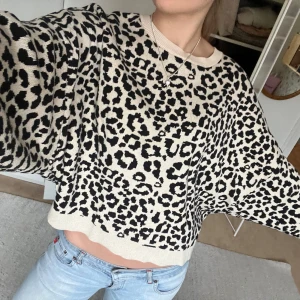 Leopardmönstrad tröja - Säljer en cool leopardmönstrad tröja i beige och svart. Tröjan har en loose passform och långa ärmar, perfekt för en avslappnad stil. Den är croppad och gjord i ett mjukt material.