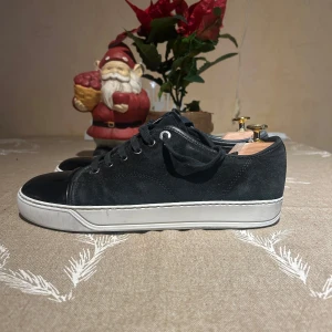 Lanvin Skor - Snygga svarta sneakers från Lanvin med snörning och vit sula. Skorna har en stilren design med en glansig svart tå och är perfekta för en avslappnad look. UK 6 och passar storlek 41-42 enligt mig. Hör av er för mer bilder