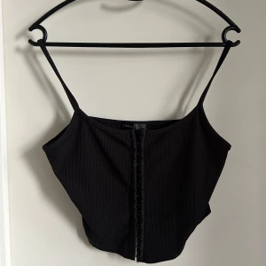 Svart ribbat linne  - Snyggt svart linne med ribbad textur och knäppning framtill. 