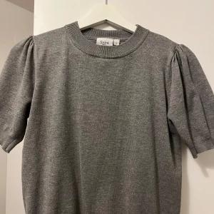 Grå tröja från Saint Tropez - Säljer en stilren grå tröja från Saint Tropez. Tröjan har korta ärmar med puffdetaljer och en rund halsringning. Perfekt för en avslappnad look.