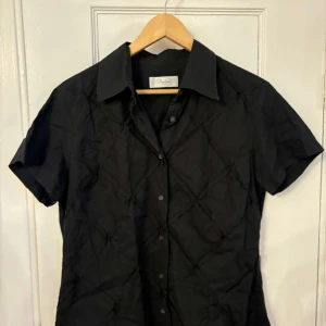 Svart kortärmad skjorta från Stenströms - Snygg svart kortärmad skjorta från Stenströms. Skjortan har en klassisk krage och knappar framtill. Perfekt för en stilren look.