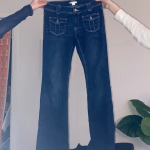 Blå jeans från Gina Tricot - Snygga blå jeans från Gina Tricot med bootcut-stil. De har klassiska femfickor och en knapp- och dragkedjestängning. Perfekta för en avslappnad look.