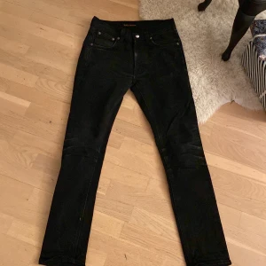 Svarta jeans från Nudie Jeans - Snygga svarta jeans från Nudie Jeans med klassisk femficksdesign. De har en slim passform och är tillverkade i ett slitstarkt denimtyg. Perfekta för en stilren look. De passar någon som är ca 174 cm lång och modellen är Lean dean som sitter slim. Ny pris ca 1700kr- mitt pris 375 men kan gå ner i pris till 325 i snabb affär!!!
